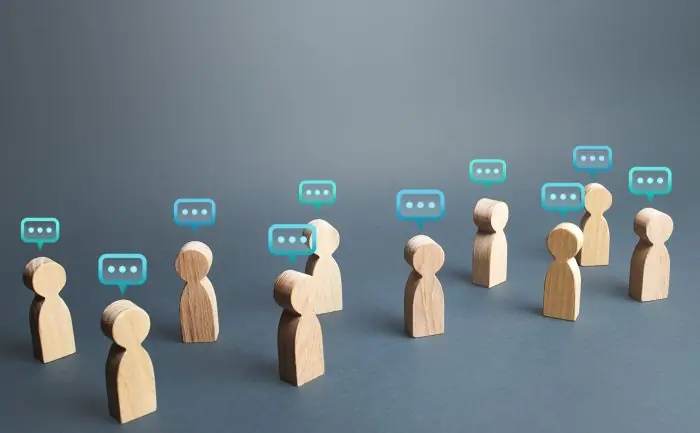 Wooden figures with chat bubbles above their heads, representing conversation among a group of people