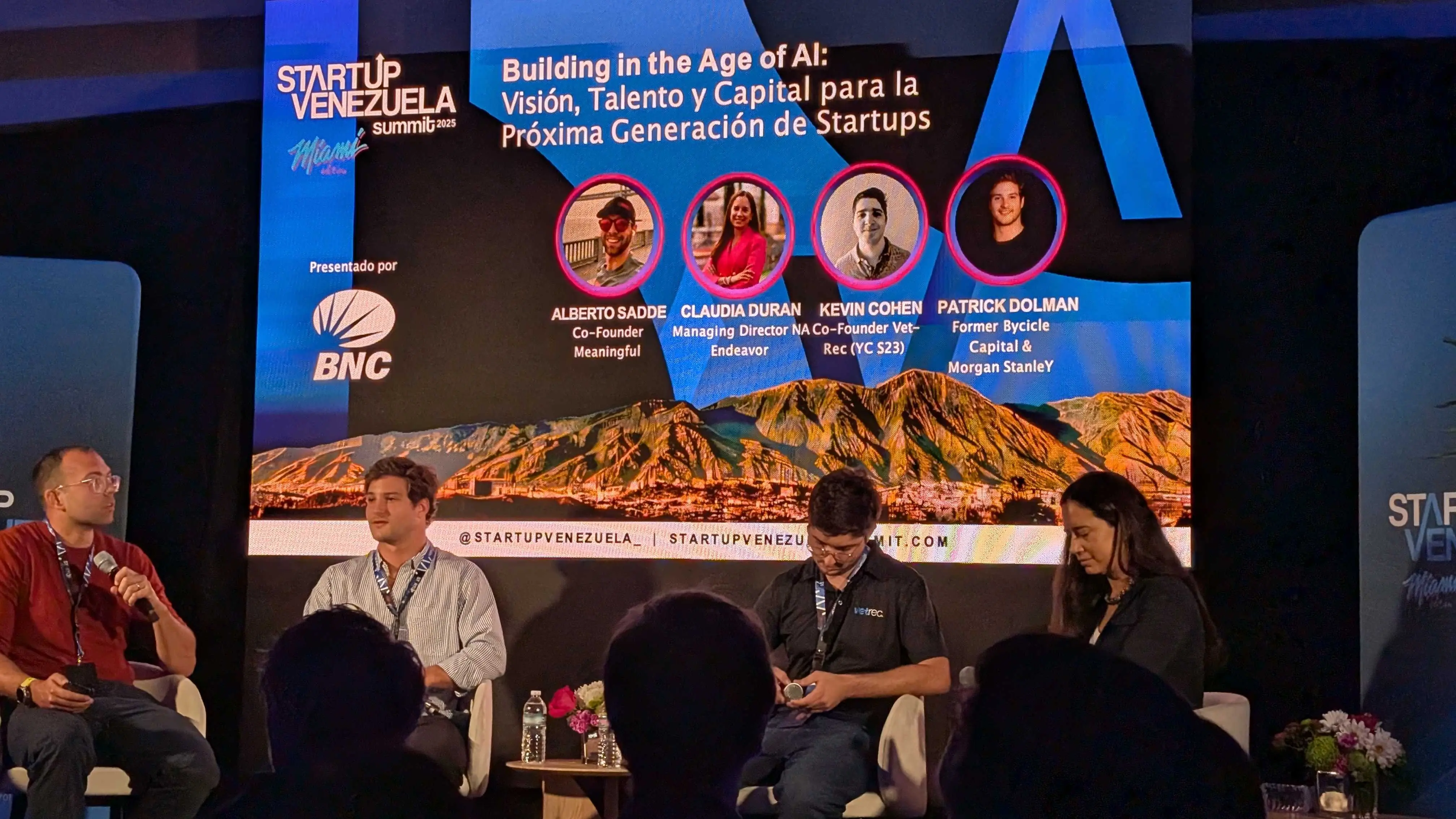 Panel at Startup Venezuela Summit 2025 on building in the age of AI, with four speakers on screen and three seated on stage